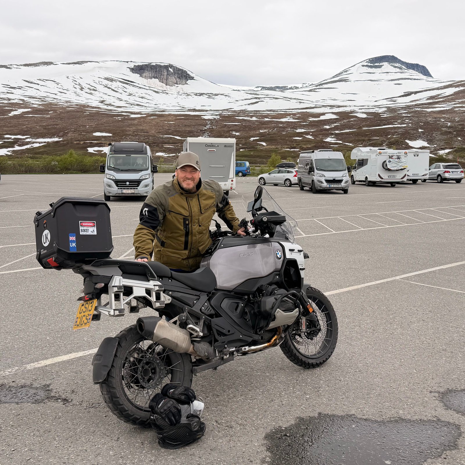 James with his BMW GS in a car park below snow covered mountains in Norway