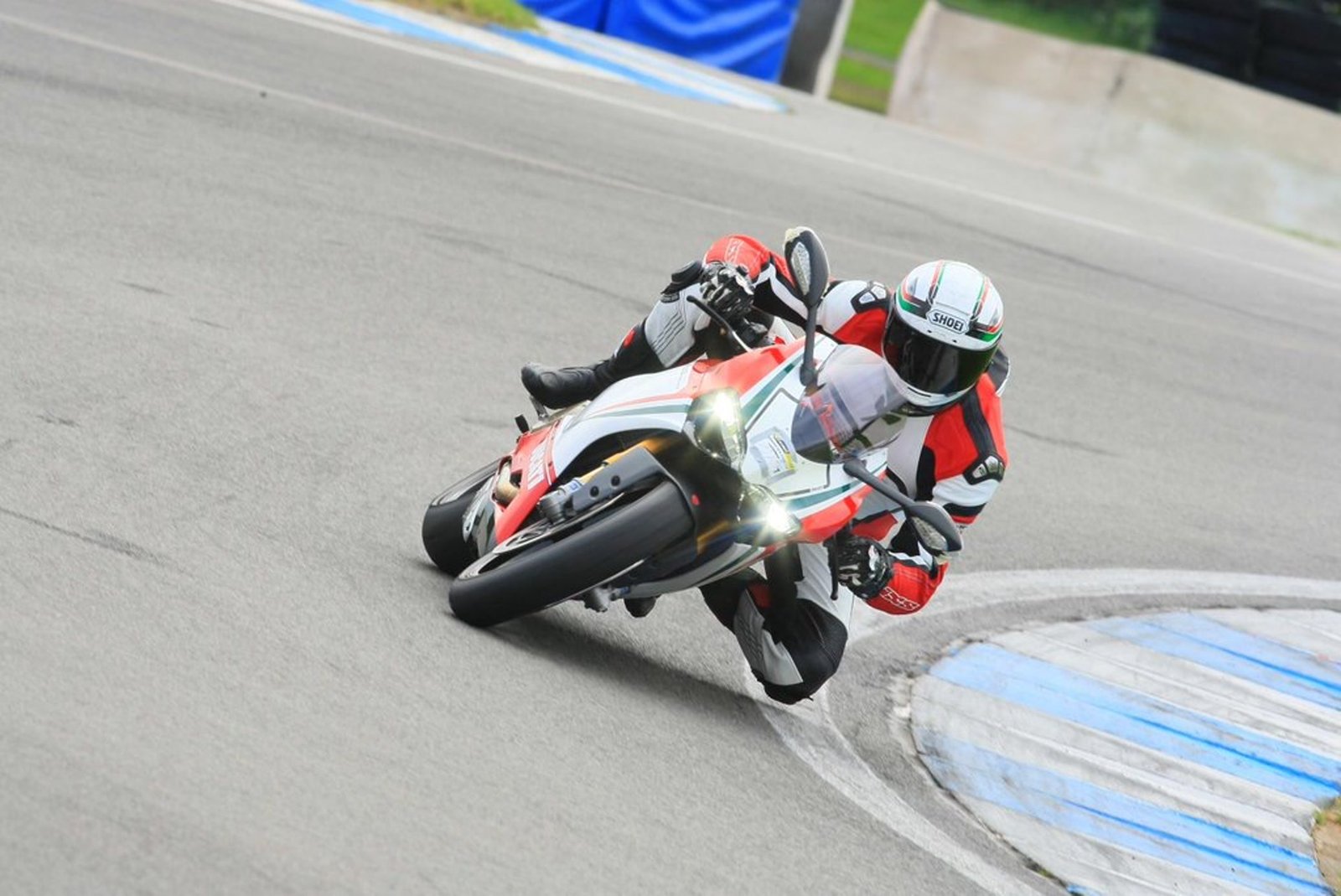 Riding a red and white superbike hard through a corner on track