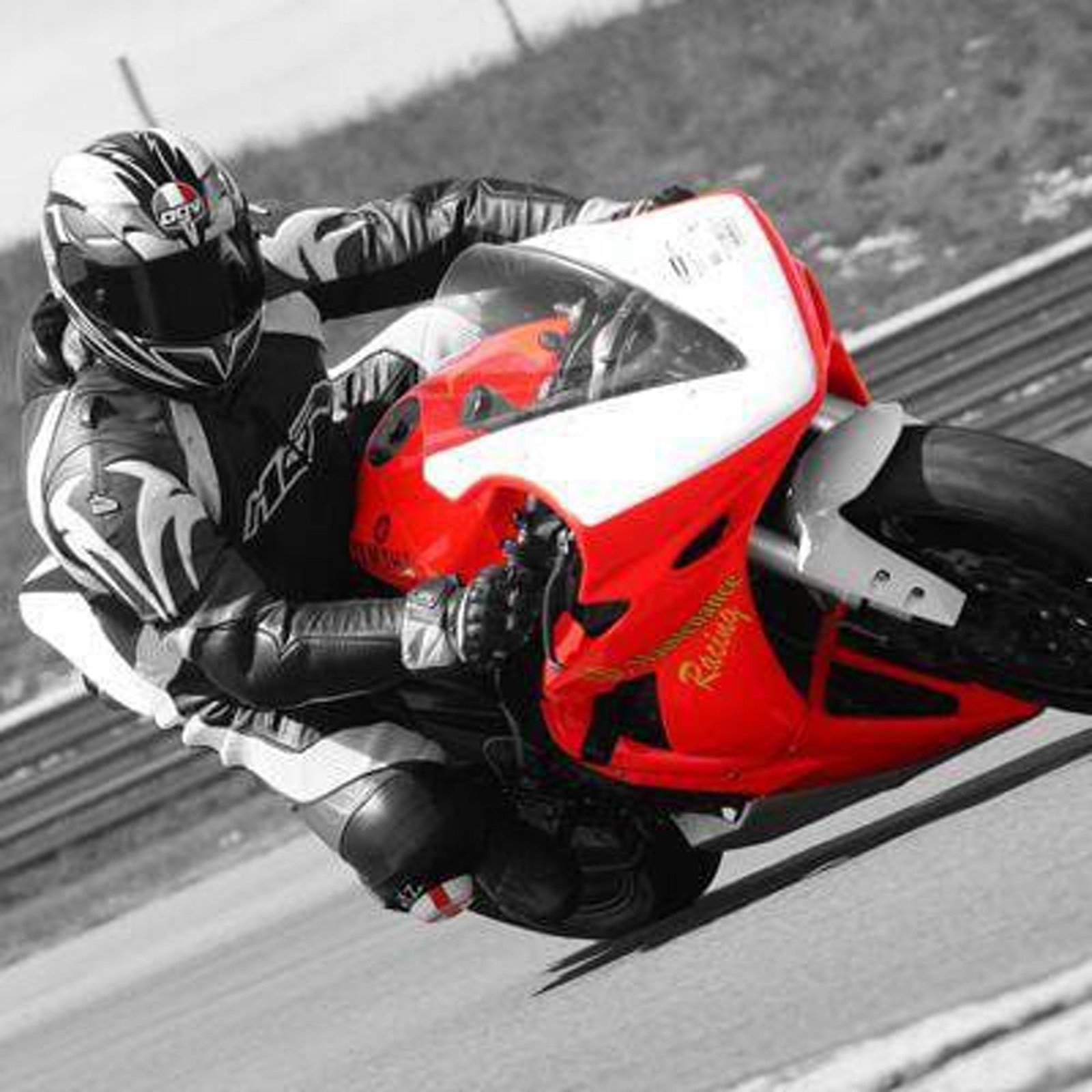 Black and white track photo with the red bike picked out in color